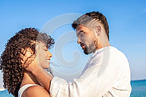 Moment of tenderness between young multiracial couple of happy lovers who look into each other`s eyes while he smilingly holds he photo