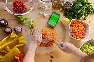 Moments of daily life in the Mediterranean cookery: flat lay top view of a young female cook cutting vegetables looking at her