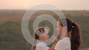 Mommy and baby hug. Mom plays with her daughter and shows child sunset. Happy family, mom and daughter in field look at