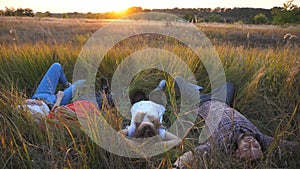 Mommy and daddy with little children lying on grass at field and enjoy resting at nature. Young couple of parents with