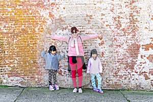 Mommy and her identical twins happy pose with old brick wall background