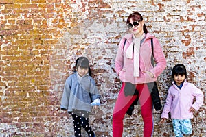 Mommy and her identical twins happy pose with old brick wall background