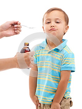 Mommy knows best. Shot shot of a young boy being given some medicine on a spoon by his mother.