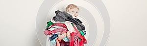 Mommy little helper. Adorable funny child arranging organazing clothing. Kid holding messy stack pile of clothes things. Home