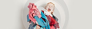 Mommy little helper. Adorable funny tired child arranging organazing clothing. Kid holding messy stack pile of clothes things.