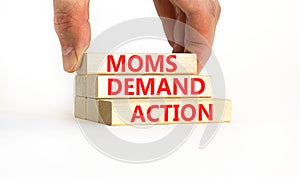 Moms demand action symbol. Concept words Moms demand action on wooden blocks on a beautiful white table white background.