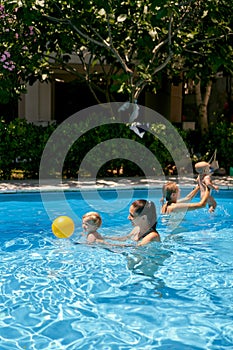 Moms with small children play with a ball in the pool