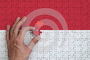 Monaco flag is depicted on a puzzle, which the man`s hand completes to fold