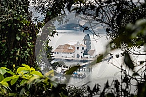 Monastery Vlacherna and the Mouse Island at clouds rainy weather through branches of trees, sea gulf, the airport runway