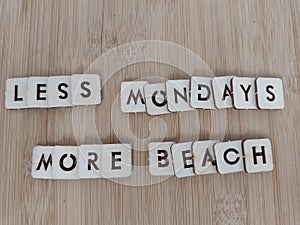 Less Mondays more beach message written on wood blocks on a wood background