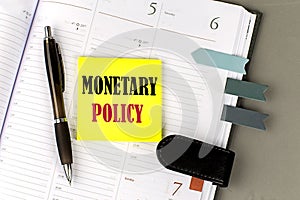 MONETARY POLICY word on the yellow sticky with office tools on daily planner