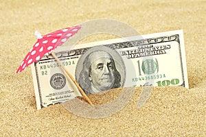 Money american hundred dollar bills in the beach sand under red and white dots sunshade photo