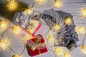 Money as a gift. Dollars with present box and lights. Christmas or birthday day. Sale concept shopping