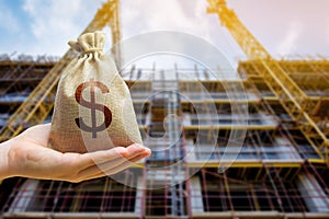 A money bag against the background of a building under construction. The concept of investing money in the construction and