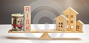 Money bag, blocks with the word Risk and a wooden house on the scales. The concept of losing money when investing in real estate.