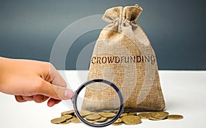 Money bag with coins with the word crowdfunding. Voluntary association of money or resources via the Internet. Support recipients