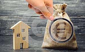 Money bag with euro sign and wooden house. The concept of real estate investing. The accumulation of money to buy a home. Rent