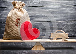 A money bag and a heart with a miniature wooden car on the scales. Auto insurance. Accumulation of money to buy a car. Saving