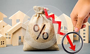 Money bag with percents, down arrow and miniature houses. The concept of low interest rates on mortgage loans or rentals. The