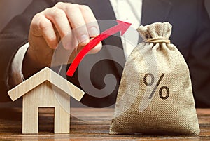 Money bag with percents, up arrow and house. The concept of high interest rates on mortgage loans or rentals. The percentage of