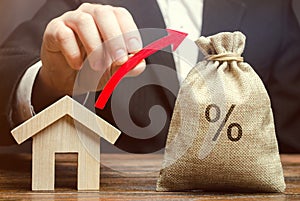 Money bag with percents, up arrow and house. The concept of high interest rates on mortgage loans or rentals. The percentage of photo