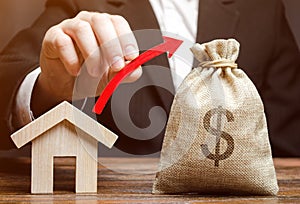 A money bag and a red arrow in the hands of a man near a house. The concept of real estate market growth. Price increase.