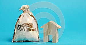 Money bag and wooden house. Concept of real estate market budget. Investment in construction. Saving money to buy a home or