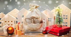 Money bag, wooden houses, Christmas tree and gifts. Christmas Sale of Real Estate. New Year discounts for buying housing. Purchase