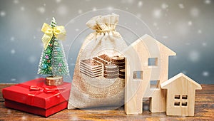 Money bag, wooden houses, Christmas tree and gifts. Christmas Sale of Real Estate. New Year discounts for buying housing. Purchase