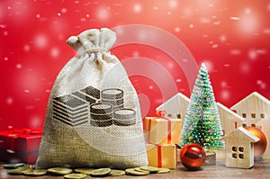 Money bag, wooden houses, Christmas tree and gifts. Christmas Sale of Real Estate. New Year discounts for buying housing. Business