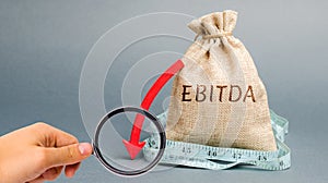 Money bag with the word Ebitda and down arrow. Earnings before interest, taxes, depreciation and amortization. Problems with