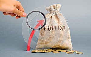 Money bag with the word Ebitda and up arrow. Earnings before interest, taxes, depreciation and amortization. Business income