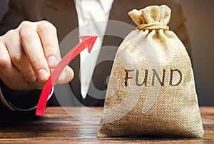 Money bag with the word Fund and up arrow. The concept of increasing the payroll. Investing in securities investors. Growing