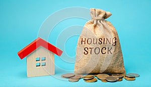 A money bag with the word Housing stock and a miniature house. Residential buildings and premises intended for permanent residence