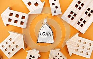 Money bag with the word Loan and wooden houses around. The concept of mortgage housing and real estate loans. Buy an apartment on