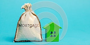 Money bag with the word Mortgage and wooden house. The accumulation of money to pay interest rates on mortgages. Buying a property photo