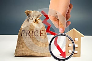 Money bag with word price, down arrow and wooden house. The concept of falling property prices. Lower housing prices. Low rent.