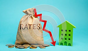 Money bag with the word Rates, down arrow and wooden house. The concept of reducing interest rates on mortgages. Low rental rate photo