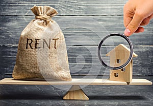 Money bag with the word Rent and a wooden house on the scales. The concept of payment for rental housing. Debt repayment. To