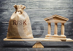 A money bag with the word Risk and a bank building on the scales. The concept of financial and economic risk. Unreliable