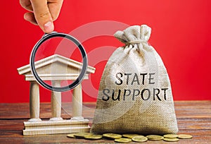 Money bag with the word State support and the bank building. Tax relief. Protection of manufacturers in the domestic market and photo