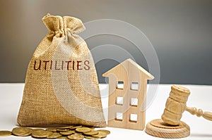 A money bag with the word Utilities, a house and a judge`s hammer. The concept of non-payment of utilities. Law and justice.