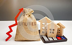 Money bag with the word Utilities and an up arrow and houses on a calculator. The concept of raising prices for the use of photo