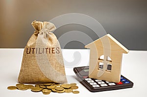 A money bag with the word Utilities and a wooden house. The concept of saving money for the payment of utilities. The accumulation