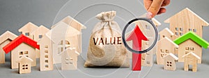 A money bag with the word Value, wooden houses and an up arrow. Concept of real estate market growth. High rental and mortgage