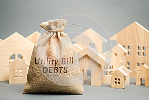 Money bag with the words Utility bill debts and wooden houses. Fines and penalties for failure to pay the debt for electricity and