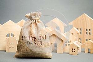 Money bag with the words Utility bill debts and wooden houses. Fines and penalties for failure to pay the debt for electricity and photo