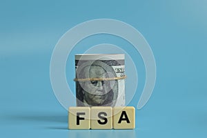 Money banknotes and alphabet letters with text FSA stands for Flexible Spending Account