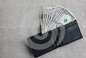 Money in the black leather wallet lying on the table cloth. Dollars for making purchases and byung things. Shopping time