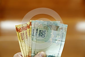 money from brazil - holding brazilian real banknotes in hand